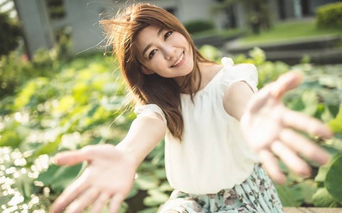 Asian woman with long brown hair reaching out