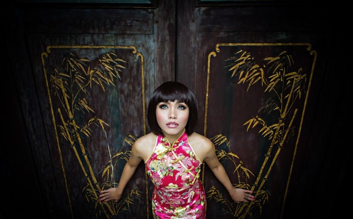 Woman in traditional Chinese dress in front of ornate doors