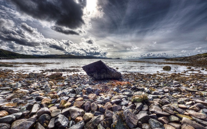Rocky shoreline with a large rock and stormy sky