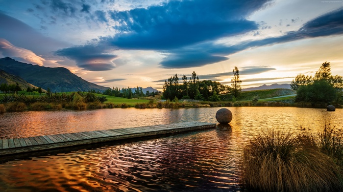 Lake at sunset with mountains and a dock