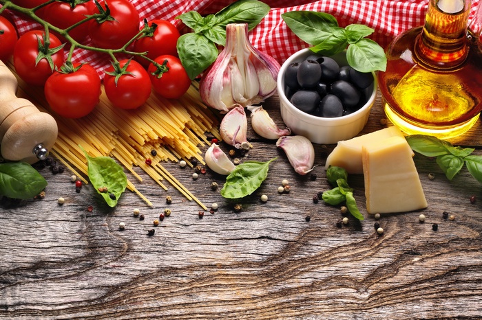 Tomatoes, pasta, garlic, olives, parmesan, and olive oil on wood