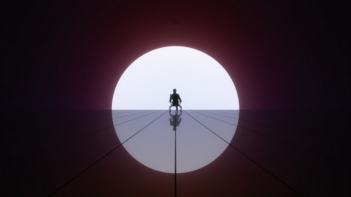 Silhouette of a person sitting in front of a large circle of light