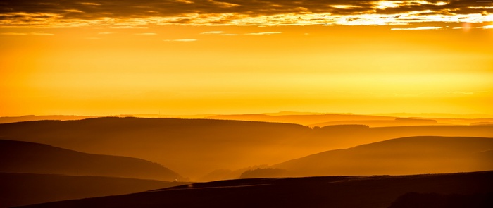 Golden sunrise over layered mountains