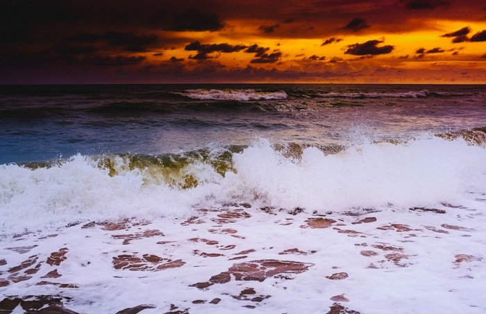 Ocean waves crashing on the shore at sunset