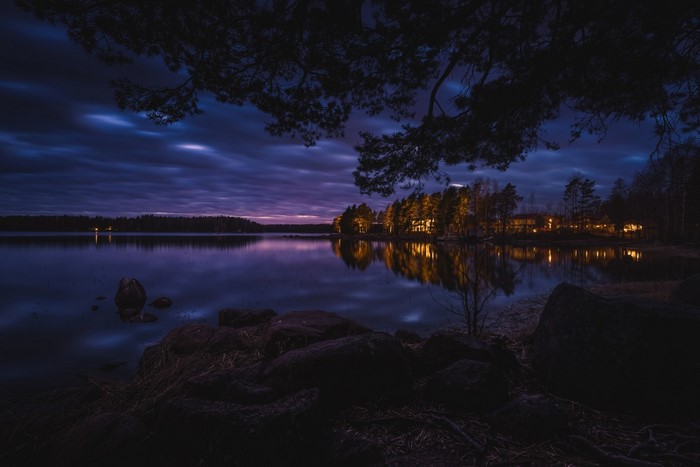 Lake at dusk with illuminated houses and trees