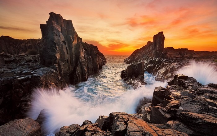 Waves crashing on rocky coast at sunset