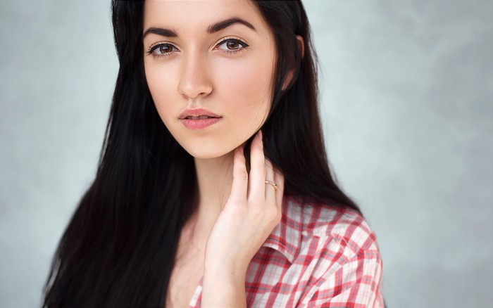 Woman with long black hair wearing a red and white checkered shirt