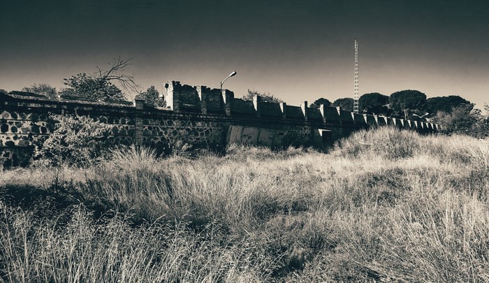 Abandoned stone wall with overgrown grass and radio tower