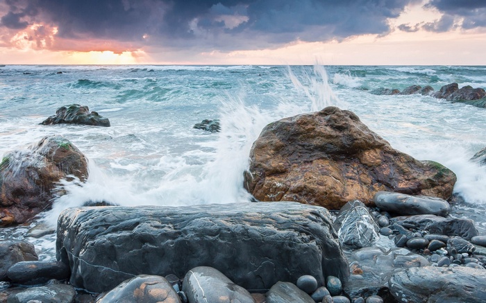 Waves crashing on rocky shore at sunset