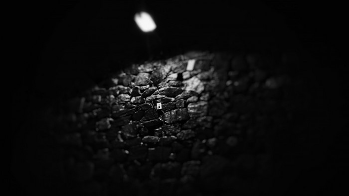 Monochrome image of a stone wall with a light source