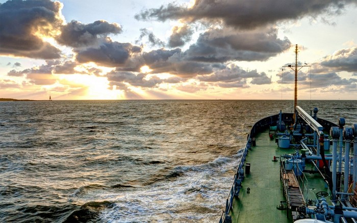 Ship sailing on the sea at sunset with clouds