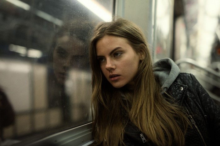 Young woman with long brown hair looking out a window