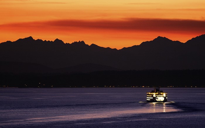 Ferry sailing on water at sunset with mountains