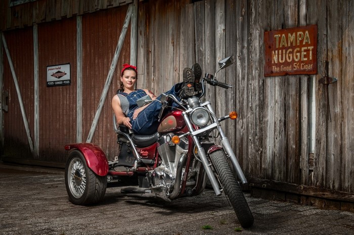Woman in overalls on a red trike motorcycle