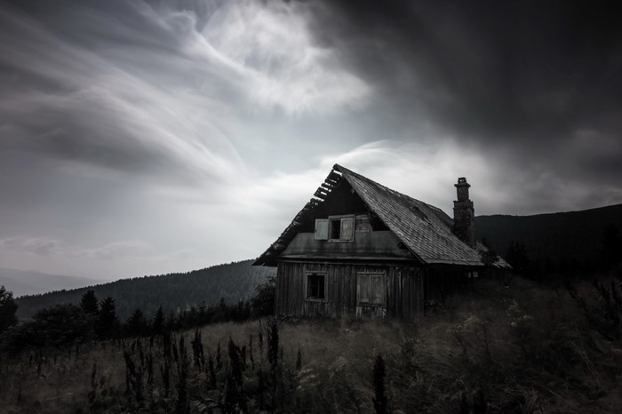 Abandoned wooden house on a hill under a cloudy sky