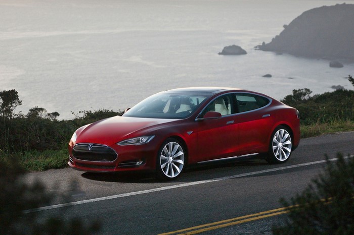 Red Tesla Model S parked on a coastal road
