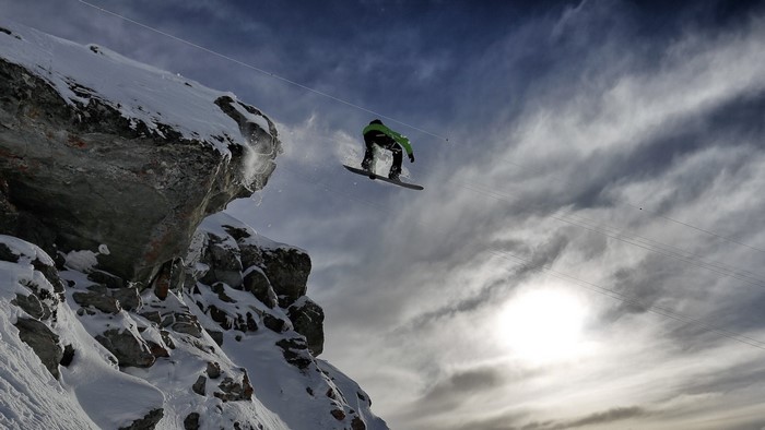 Snowboarder jumping off a snowy cliff