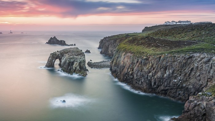 Serene Coastal Cliff and Natural Rock Arch at Sunset