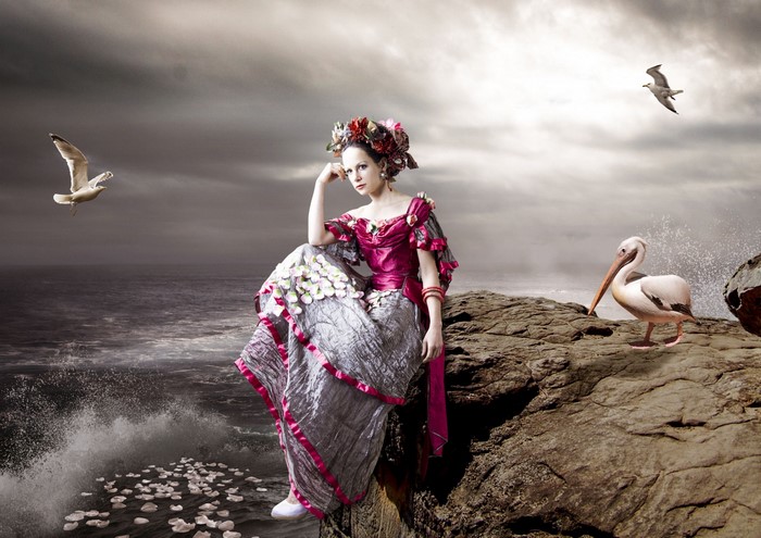 Woman in fantasy dress with flowers and birds by the sea