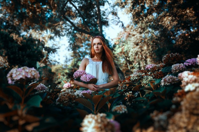Woman in white dress holding flowers in a garden