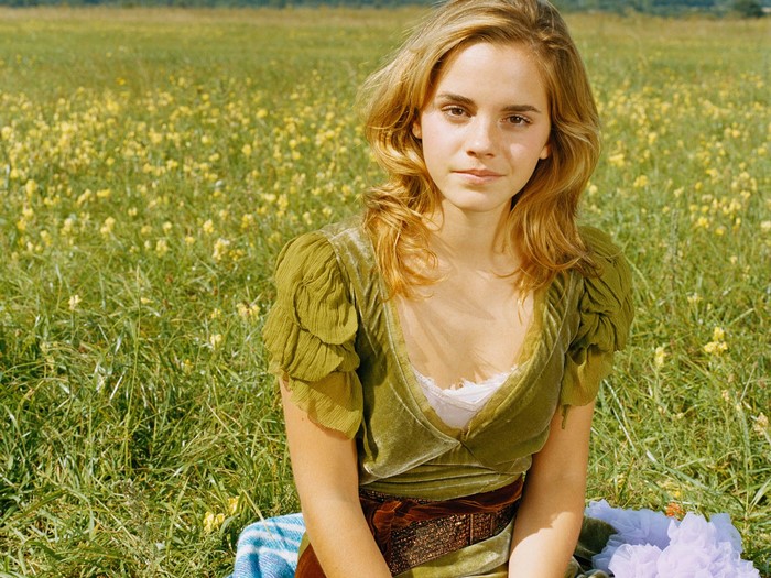 Emma Watson sitting in a field of yellow flowers