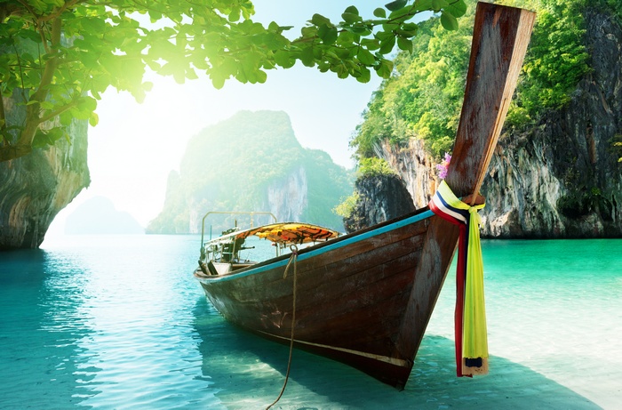 Longtail boat in a tropical bay with limestone cliffs