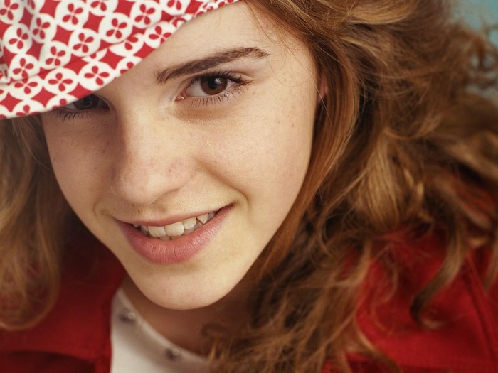 Emma Watson smiling wearing a red and white hat