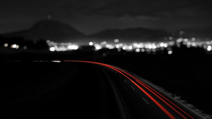 Long exposure of red light trails on a dark road at night