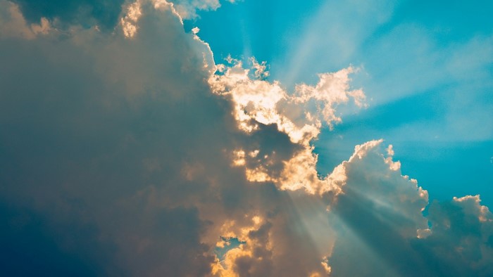 Sunlight streaming through clouds in a blue sky