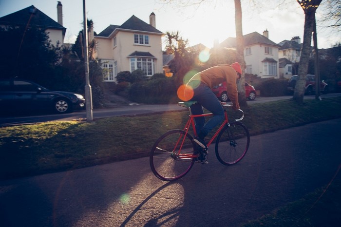 Man riding a bicycle on a street with houses