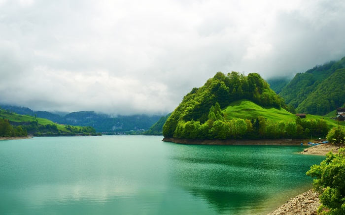 Turquoise lake and green mountains under cloudy sky