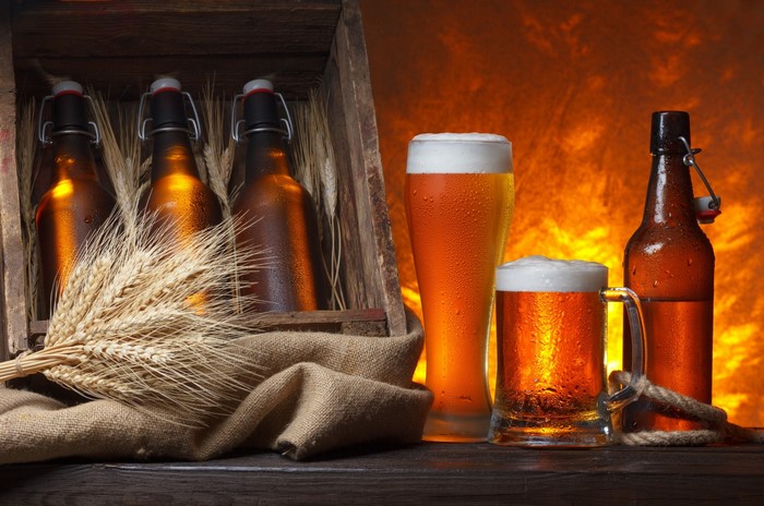 Beer bottles and glasses with wheat on a wooden surface