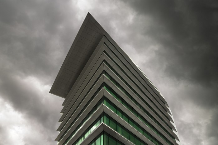 Modern building with green windows against stormy sky