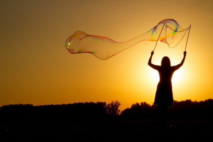 Silhouette of a woman making giant bubbles at sunset