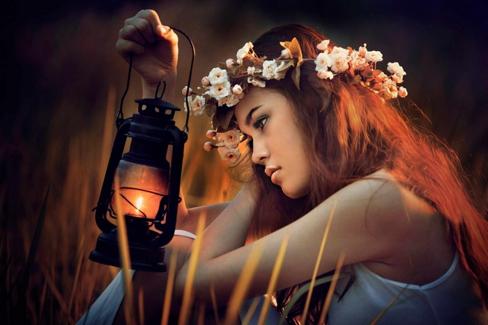 Woman with flower crown holding a lantern