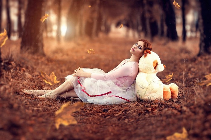 Woman with teddy bear in autumn forest