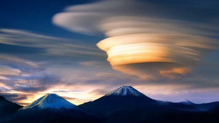Lenticular clouds over mountains at sunset