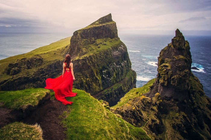 Woman in red dress on a cliff overlooking the sea