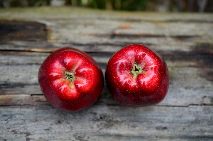 Two red apples on a wooden surface