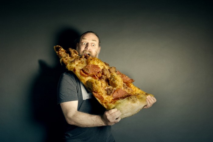 Man eating a giant slice of pizza