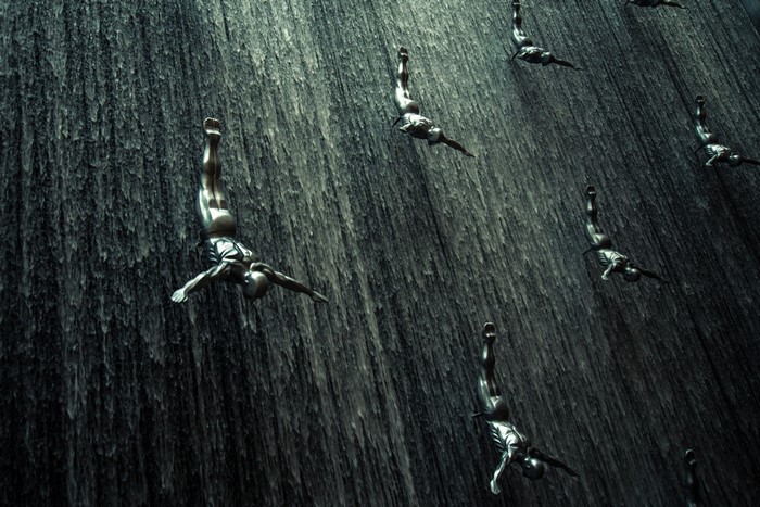 People diving down a dark waterfall
