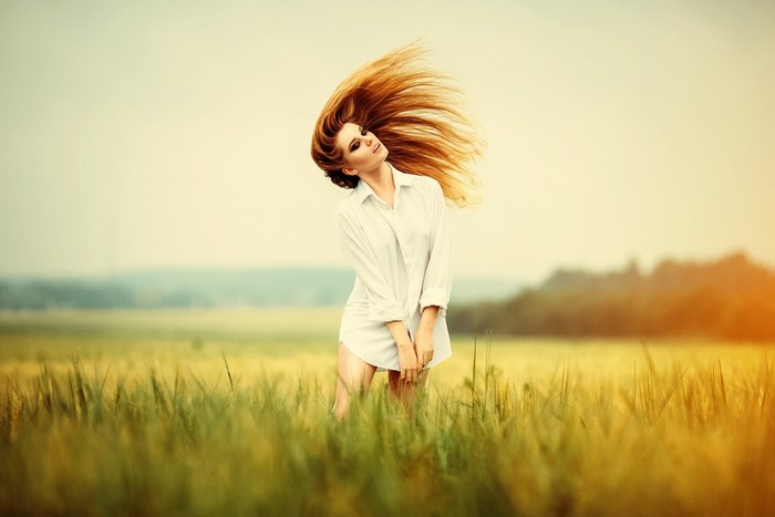 Woman with flowing red hair in a white shirt in a field