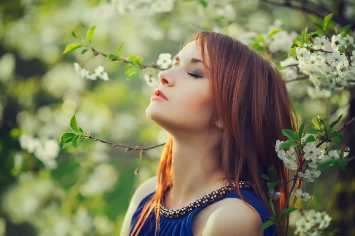 Woman with closed eyes in a blue dress among flowers