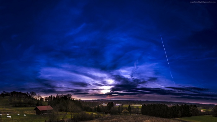 Dramatic sunset over a rural landscape with a barn