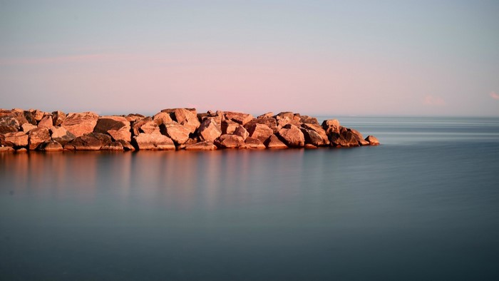 Rocky shore at sunset with calm ocean reflection