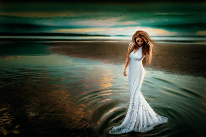 Woman in white dress on a beach at sunset