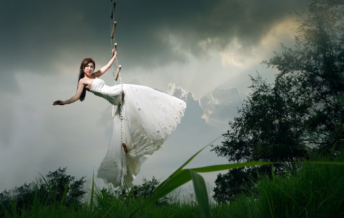 Woman in white dress climbing a rope ladder