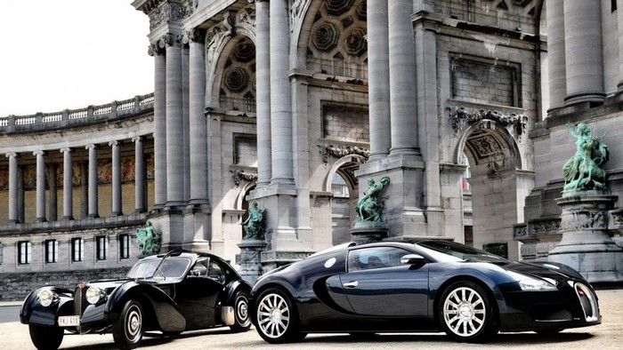 Two Bugatti cars in front of a grand building