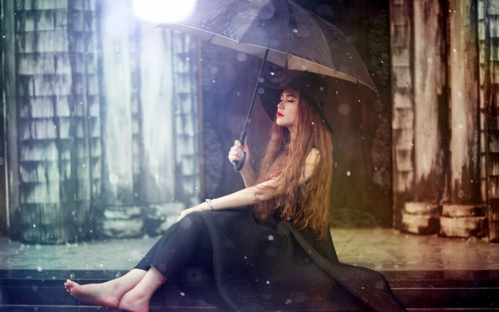 Woman in black dress holding umbrella in the rain