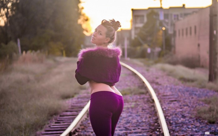 Woman in purple leggings and jacket on railroad tracks